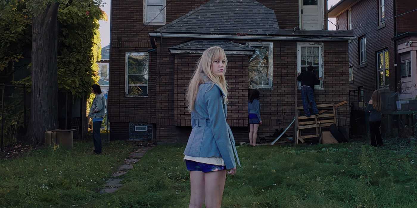 Jay stands in front of an abandoned house while her friends find a way in