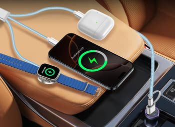 Smartphone, wireless earbuds, and smartwatch charging in a car using different cables connected to a car USB charger