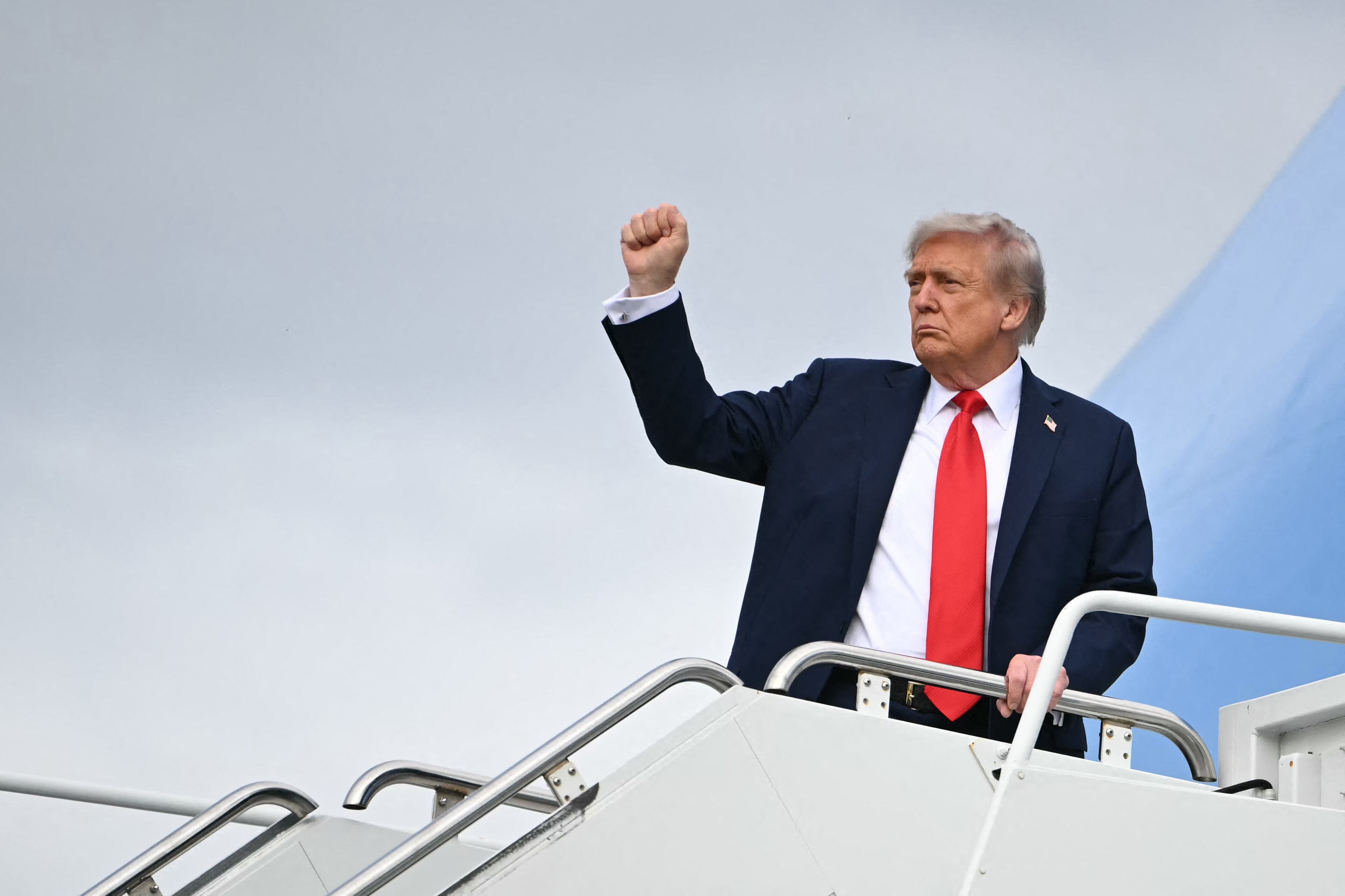President Donald Trump raises a fist as he boards Air Force One before departing from Anchorage, Alaska after a summit with the Russia's Vladimir Putin on August 15, 2025. / ANDREW CABALLERO-REYNOLDS / AFP via Getty Images
