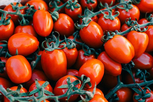 Red tomatoes with green stems, piled together