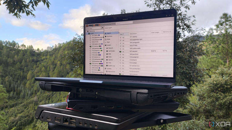 Multiple old laptops, with a MacBook displaying the Proxmox UI resting on top of them