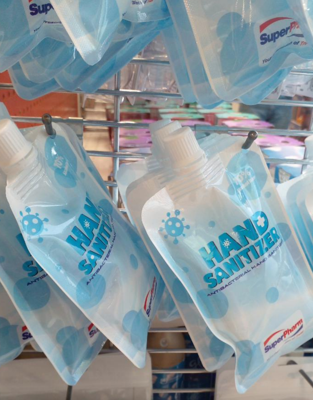 Hand sanitizer pouches hanging on a metal rack, labeled "Hand Sanitizer" by SuperPharm