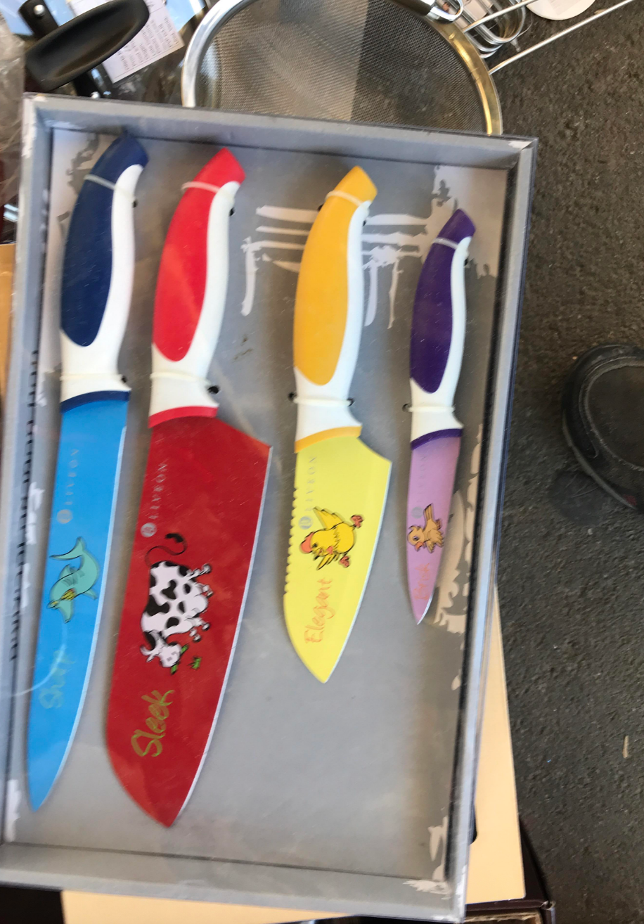 Set of four kitchen knives with colorful handles and playful animal designs on the blades, displayed in a box