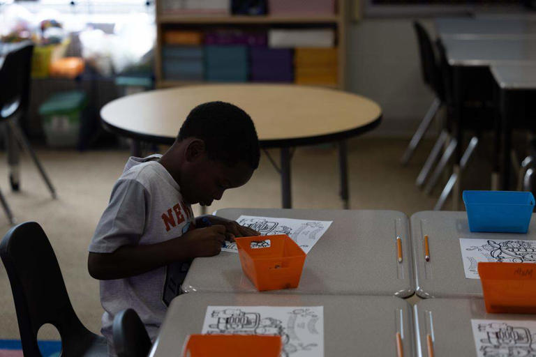 A first grader sits down to color on the first day of the 2025 school year at Dunbar Elementary in East St. Louis.