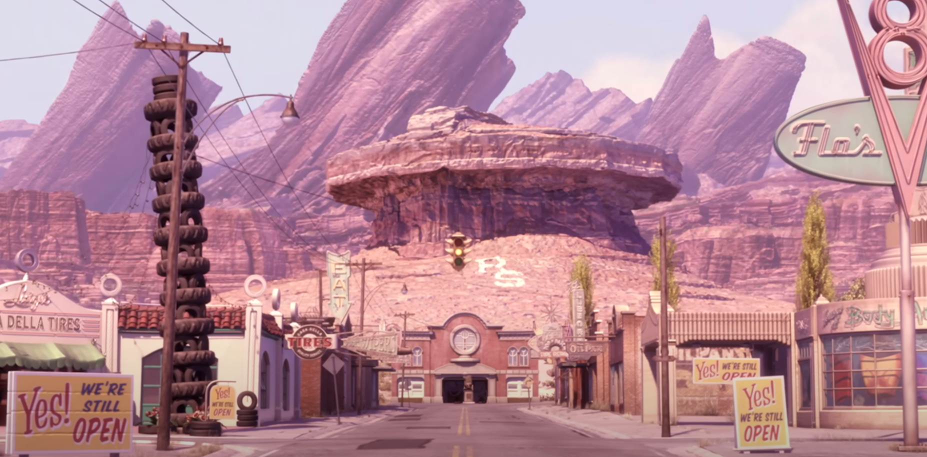 Animated desert town scene with retro diner signs, set against large rock formations, some signs read
