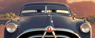 Animated car with expressive eyes looking determined in a desert landscape, from a popular animated movie