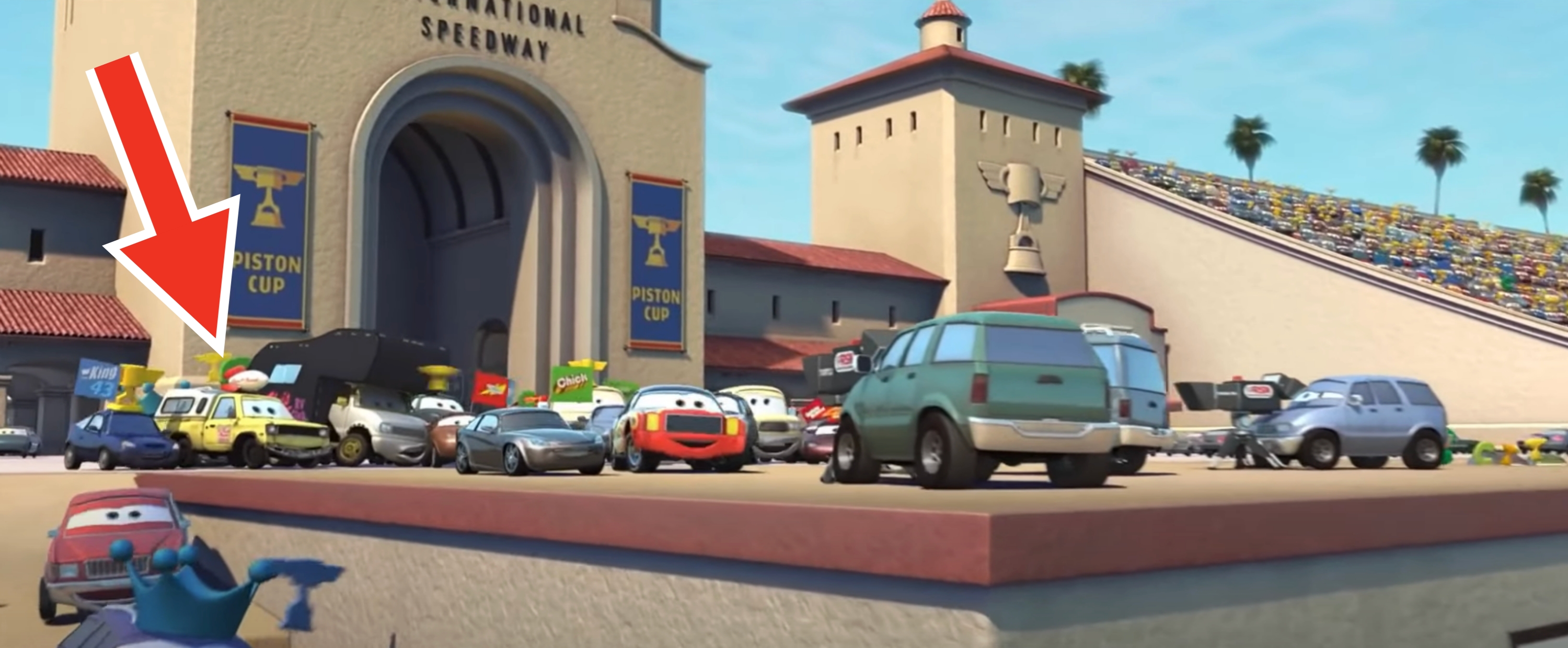 Animated cars gather outside a racetrack, hinting at a race or event scene from an animated movie