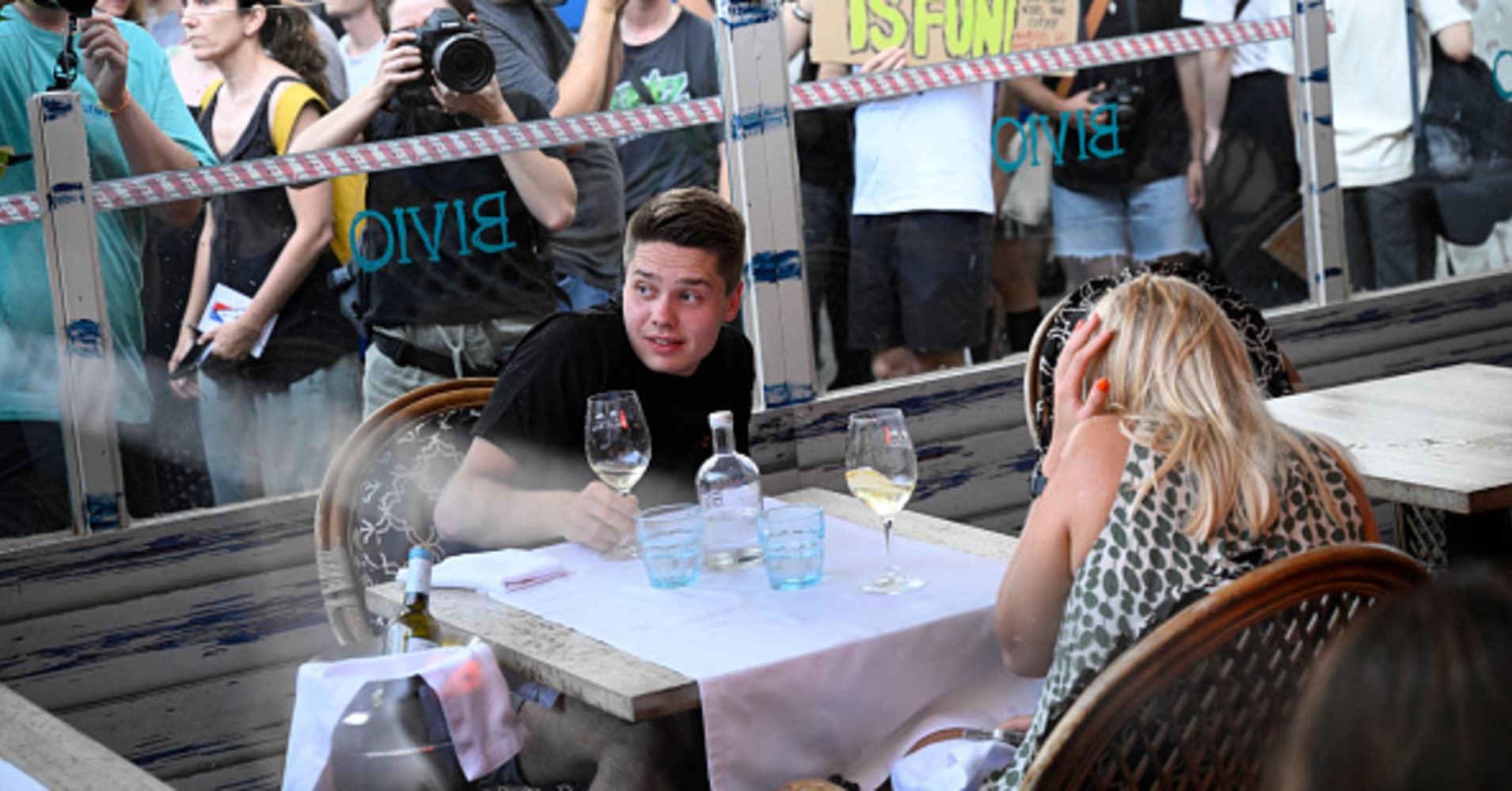 A man ducks and a woman covers her ears as protesters interrupt their meal in Barcelona on July 6, 2024.