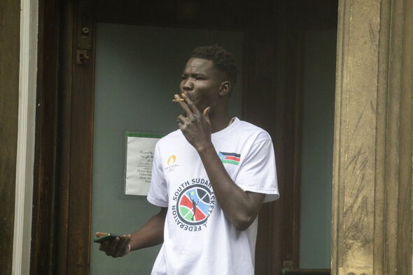 man smokes outside migrant hotel