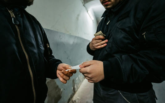 Young man meeting with dealer at night to buy dose of white powder cocaine
