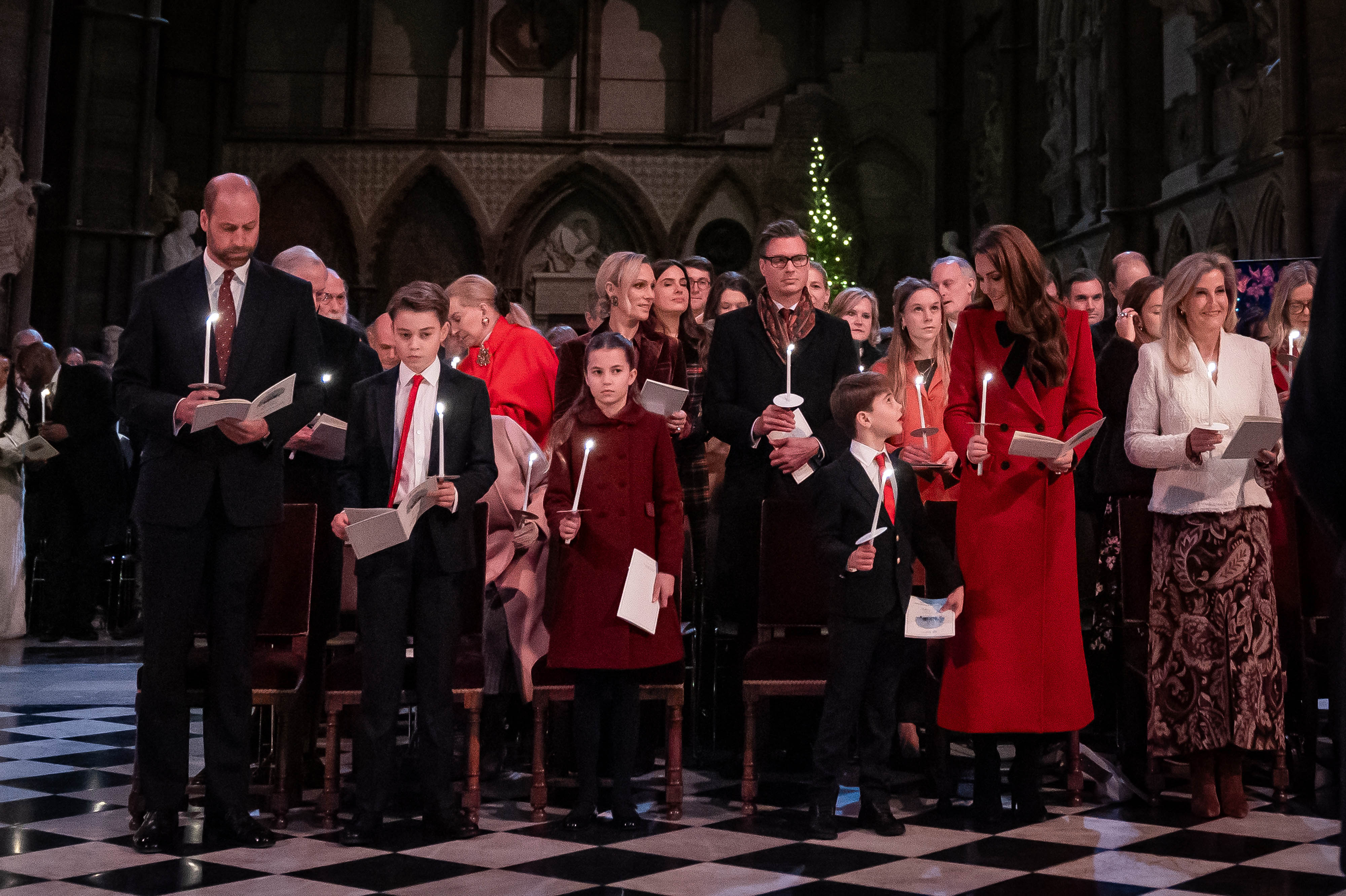 Kate Middleton holding a candle in church next to Prince William, Prince George, Princess Charlotte and Prince Louis