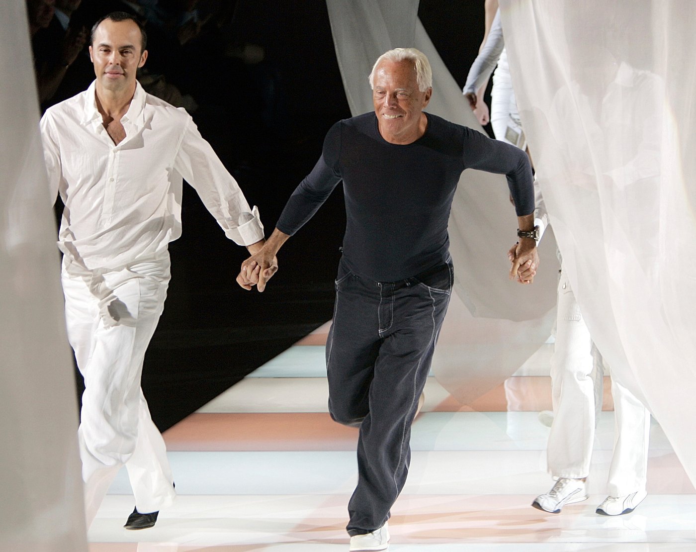 FILE - Fashion designer Giorgio Armani, center, runs on the catwalk as he acknowledges the applause of the audience after presenting the Emporio Armani Spring/Summer 2005 collection, in Milan, Italy, Sept. 27, 2004. (AP Photo/Luca Bruno, File)