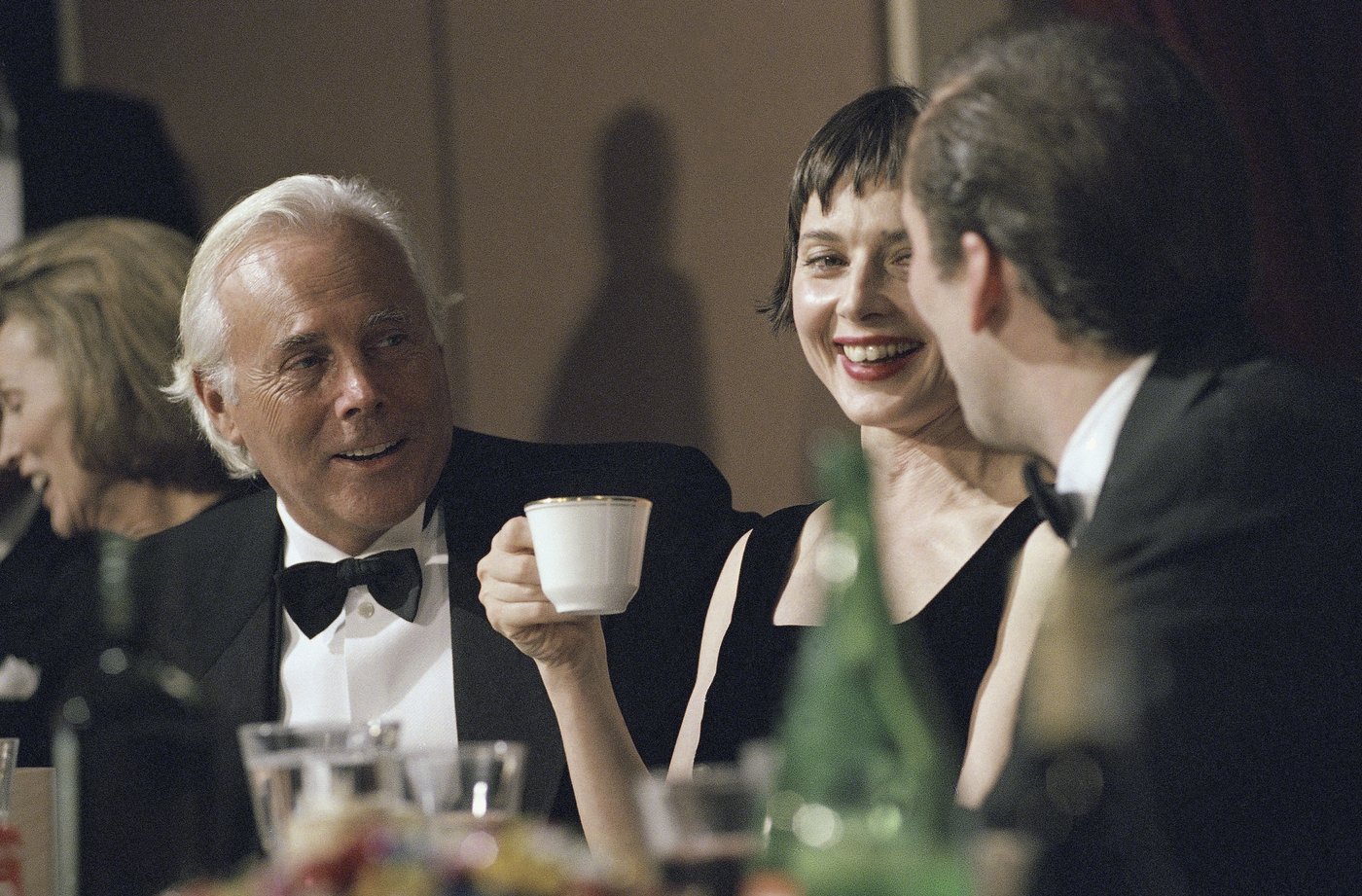 FILE - Fashion designer Giorgio Armani, left, talks with actress Isabella Rossellini and actor Nicolas Cage at a gathering of the National Italian American Foundation in Washington, Oct. 29, 1994. (AP Photo/Greg Gibson, File)