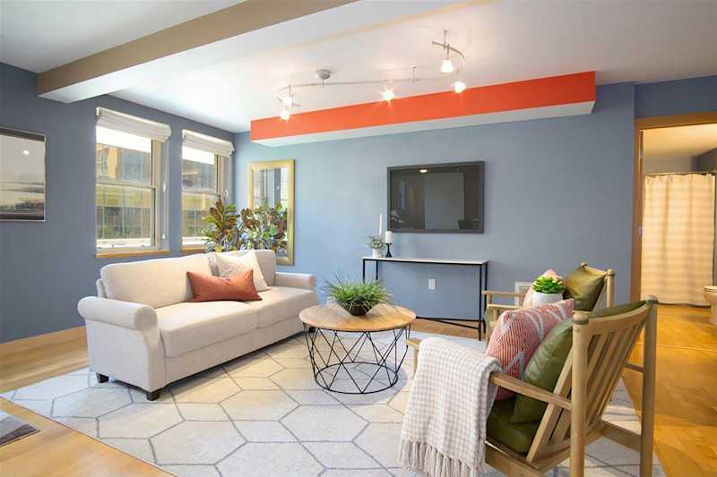 Cozy living room featuring a light sofa, green armchair, round coffee table, and wall-mounted TV.