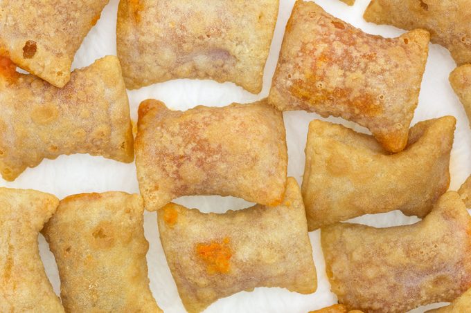 Several bite size pizza rolls on a white paper napkin that have been microwaved.