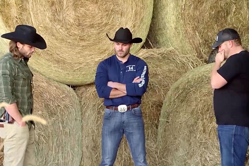 Steven McBee Jr., Jesse McBee, and Cole McBee standing in front of hay bales.