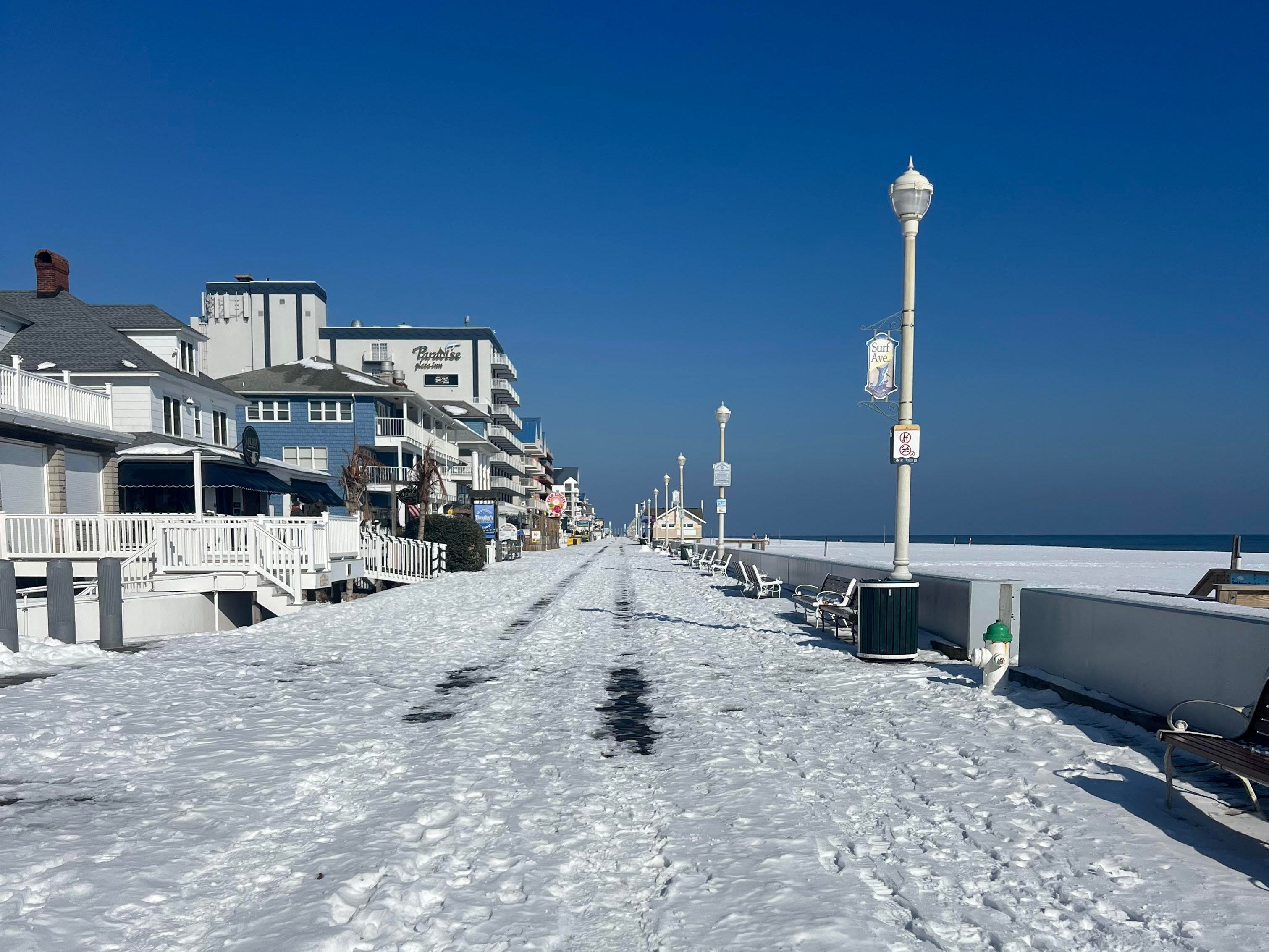 An empty beach boardwalk in Maryland covered in snow.