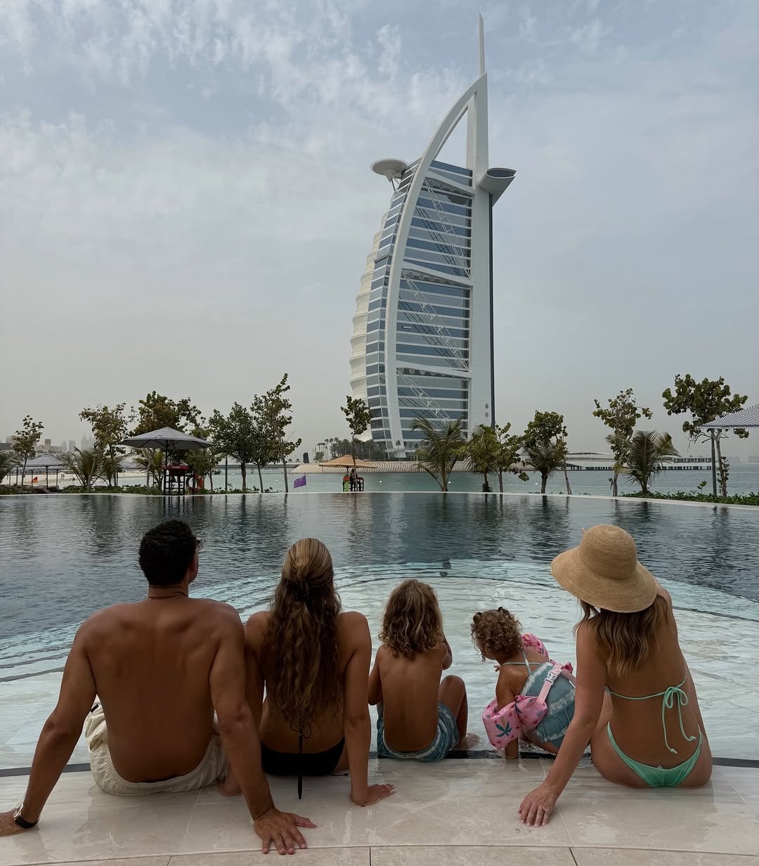 Kate Ferdinand and Rio Ferdinand sitting by the pool with three of their five children in Dubai