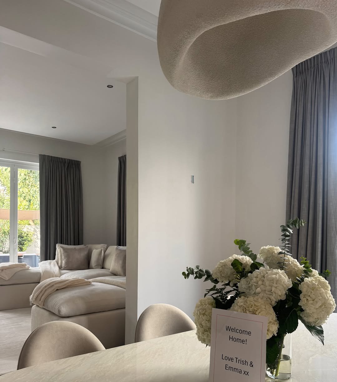 Kate and Rio Ferdinand's white living room with cream sofas and a dining table and chairs set