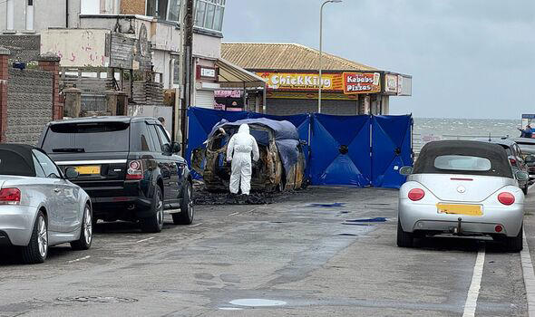 Investigators near the burnt car