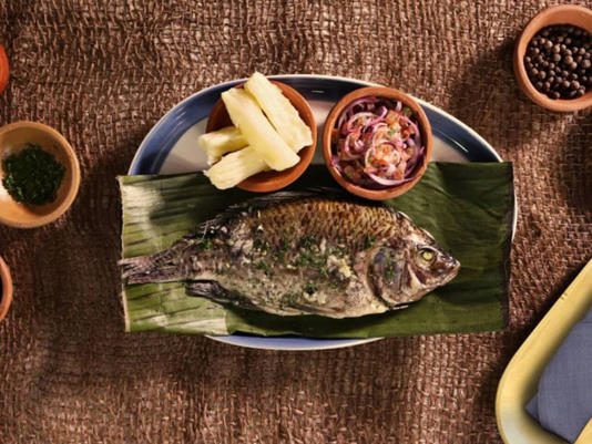 Pescado envuelto en hojas de bijao, acompañado de yuca o plátano asado.