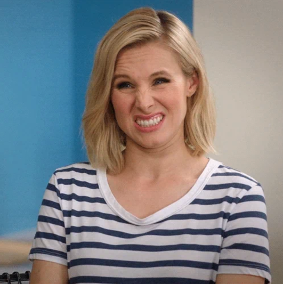 Person with short blonde hair, wearing a striped shirt, making a funny face with a scrunched nose, as if reacting with amusement or mild discomfort