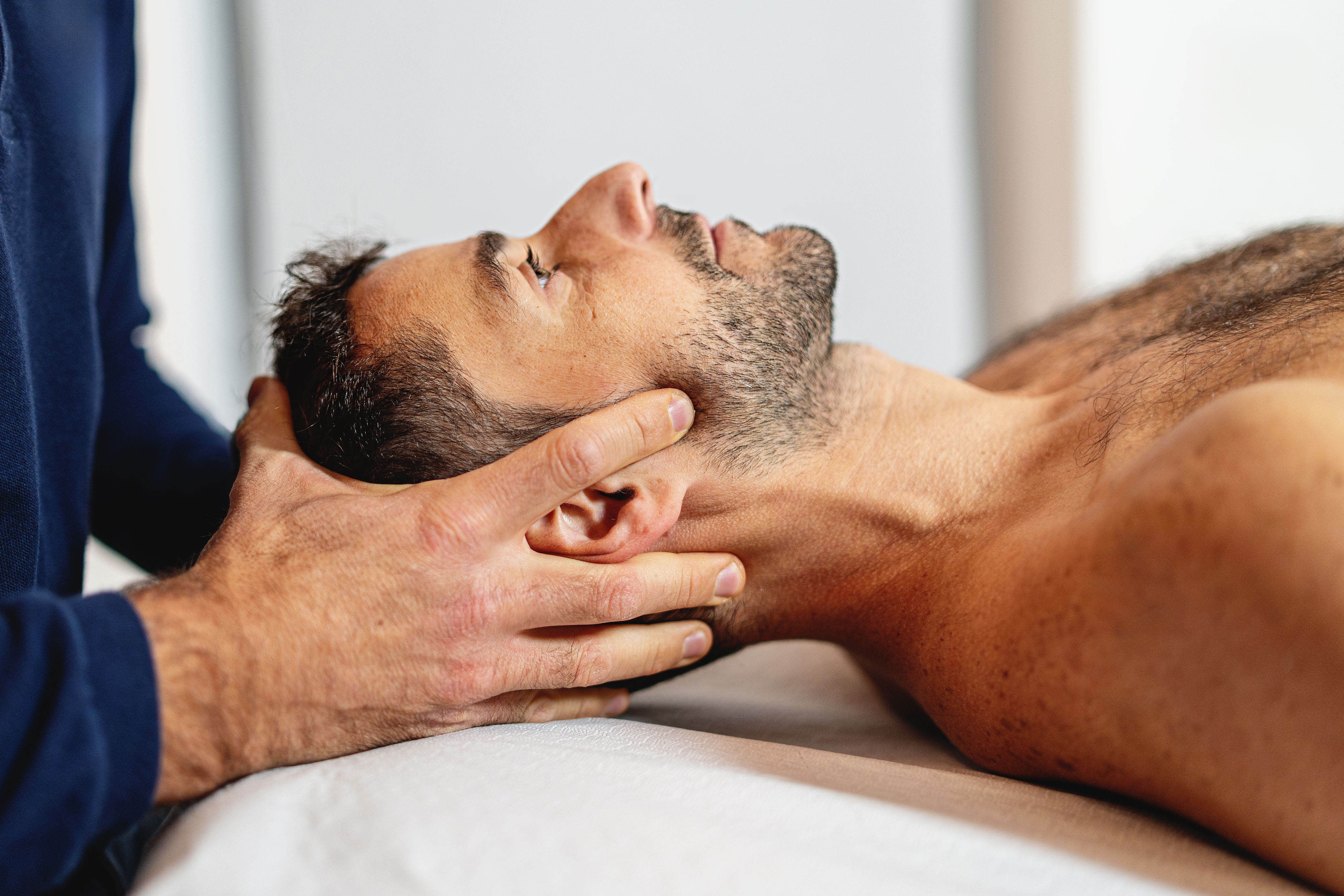 Person lying down receiving a neck massage from another person, focusing on relaxation and well-being