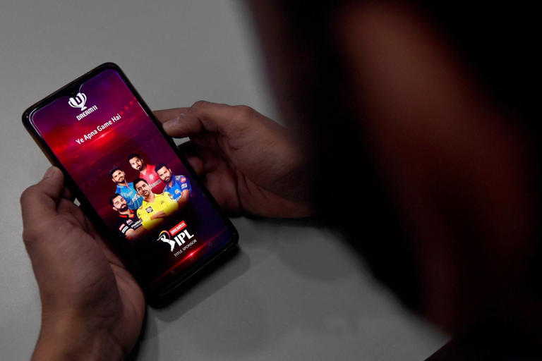 Пользователь проверяет наличие в приложении Dream11, индийской платформы для фэнтези-спорта, на своем мобильном телефоне в Нью-Дели. Фото: AFP