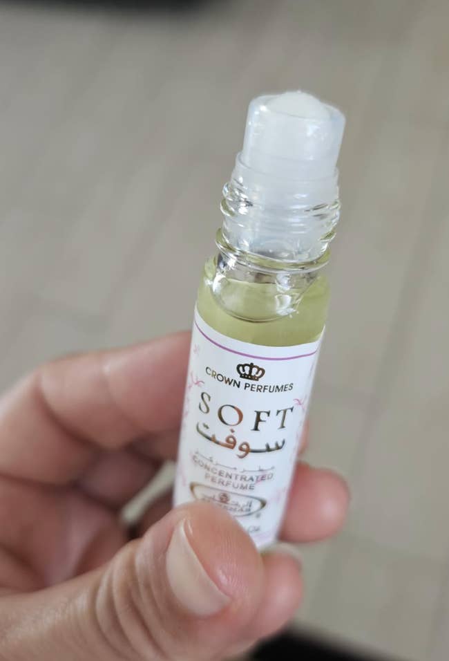 Person holding a small bottle of Crown Perfumes'