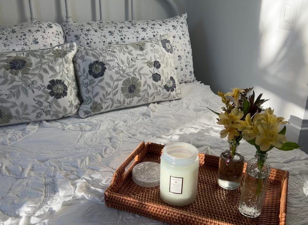 Candles on wicker tray in bed with white sheets