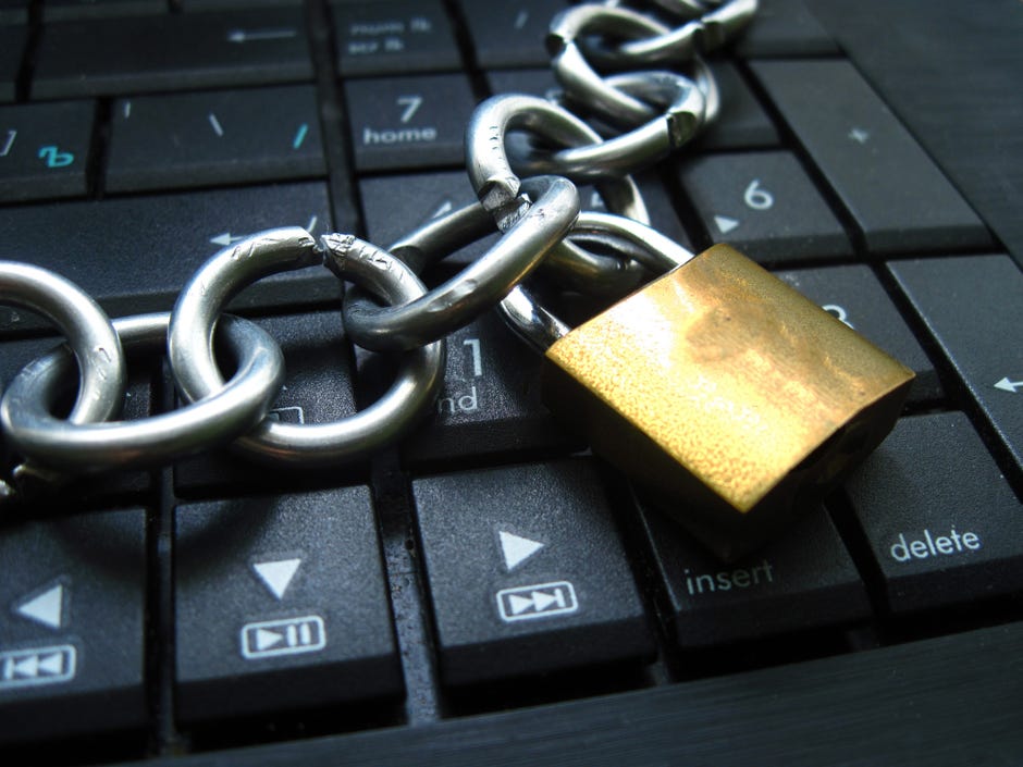 A bronze lock and chain on a black keyboard.