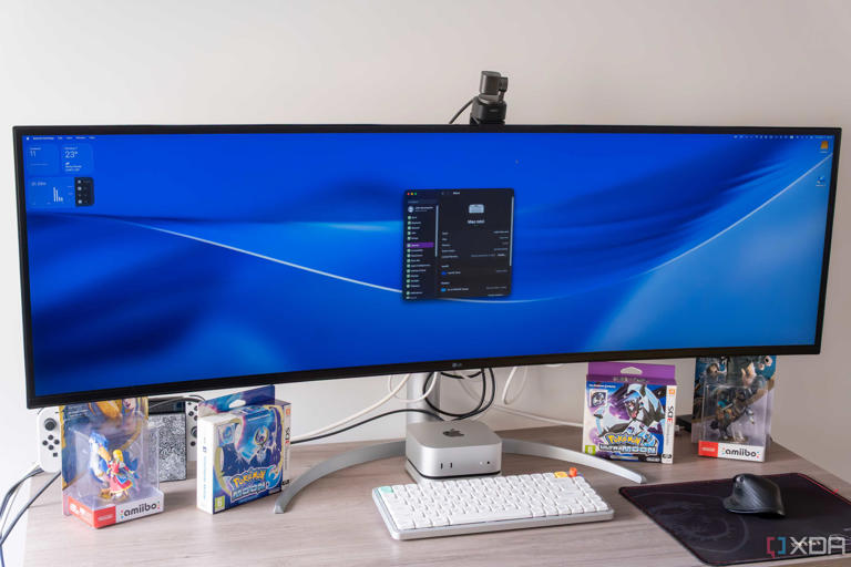 A Mac Mini connected to an ultrawide monitor showing the macOS desktop and System Settings