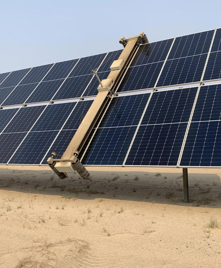 A solar panel being swept clean of dust.