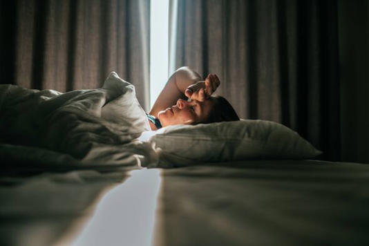 Woman awaking after sleeping well in a nice sleeping room.. Sunny daylight is coming through the curtains in the back.She had on