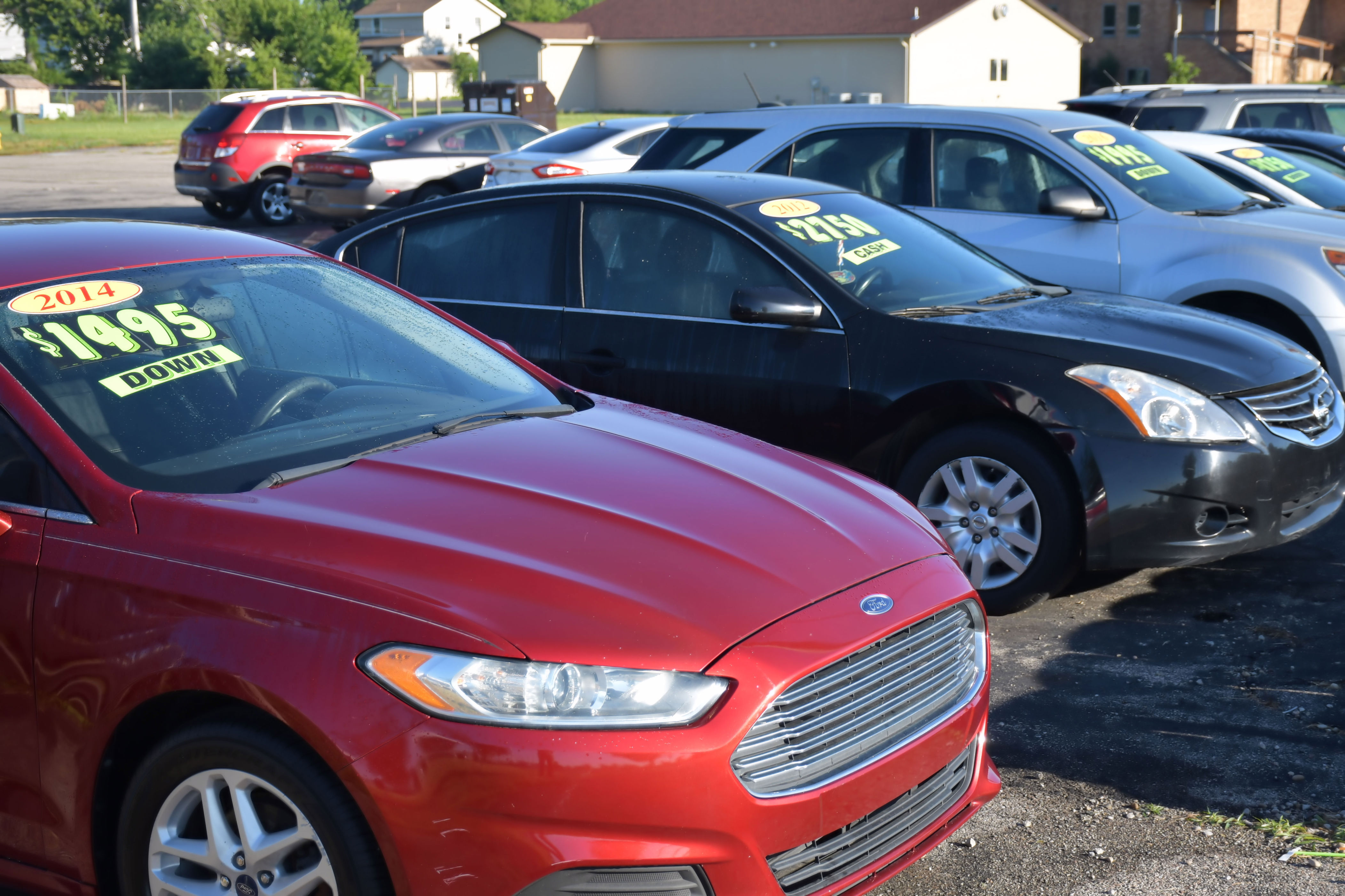 Cars parked in a lot with sale prices displayed on windshields