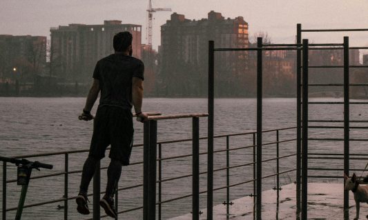 man exercising on bars outside evening