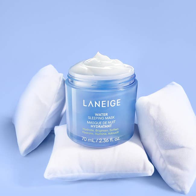 Laneige Water Sleeping Mask jar on small white pillows, showcasing its hydrating cream. Text highlights hydration benefits, suitable for shopping context