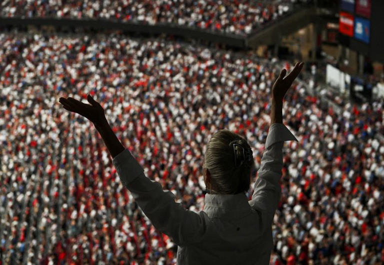 A person raises their arms while attending a memorial service for slain conservative commentator Charlie Kirk at State Farm Stadium, in Glendale, Arizona, U.S., September 21, 2025. REUTERS/Callaghan O'Hare