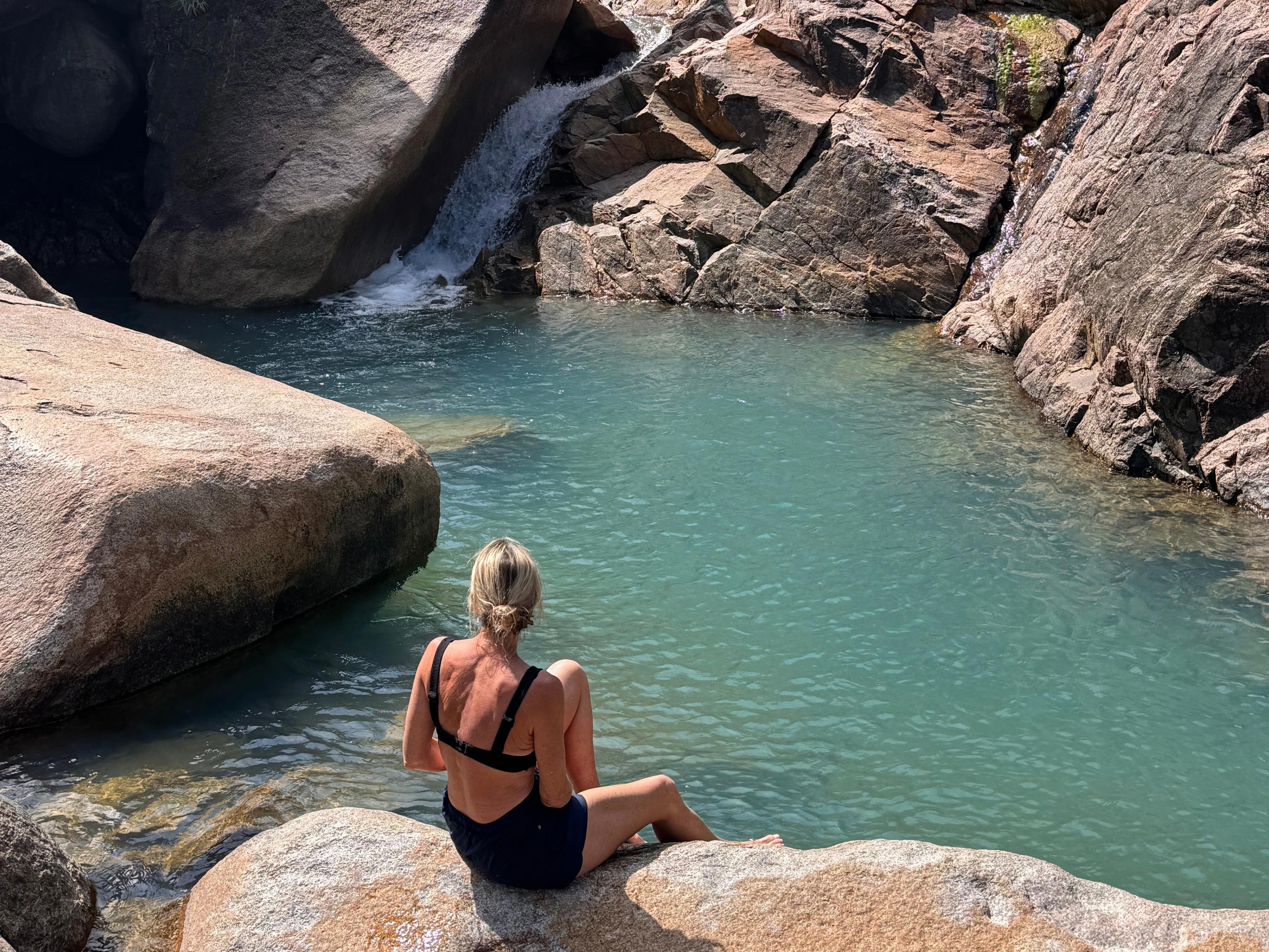 A woman sitting at the top of a waterfall.
