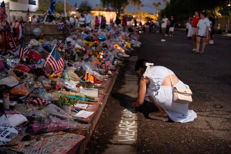 A woman writes "WE ARE CHARLIE" in chalk as she visits a tribute for slain conservative commentator Charlie Kirk at the headquarters of Turning Point USA, in Phoenix, Arizona, U.S., September 21, 2025. REUTERS/Cheney Orr