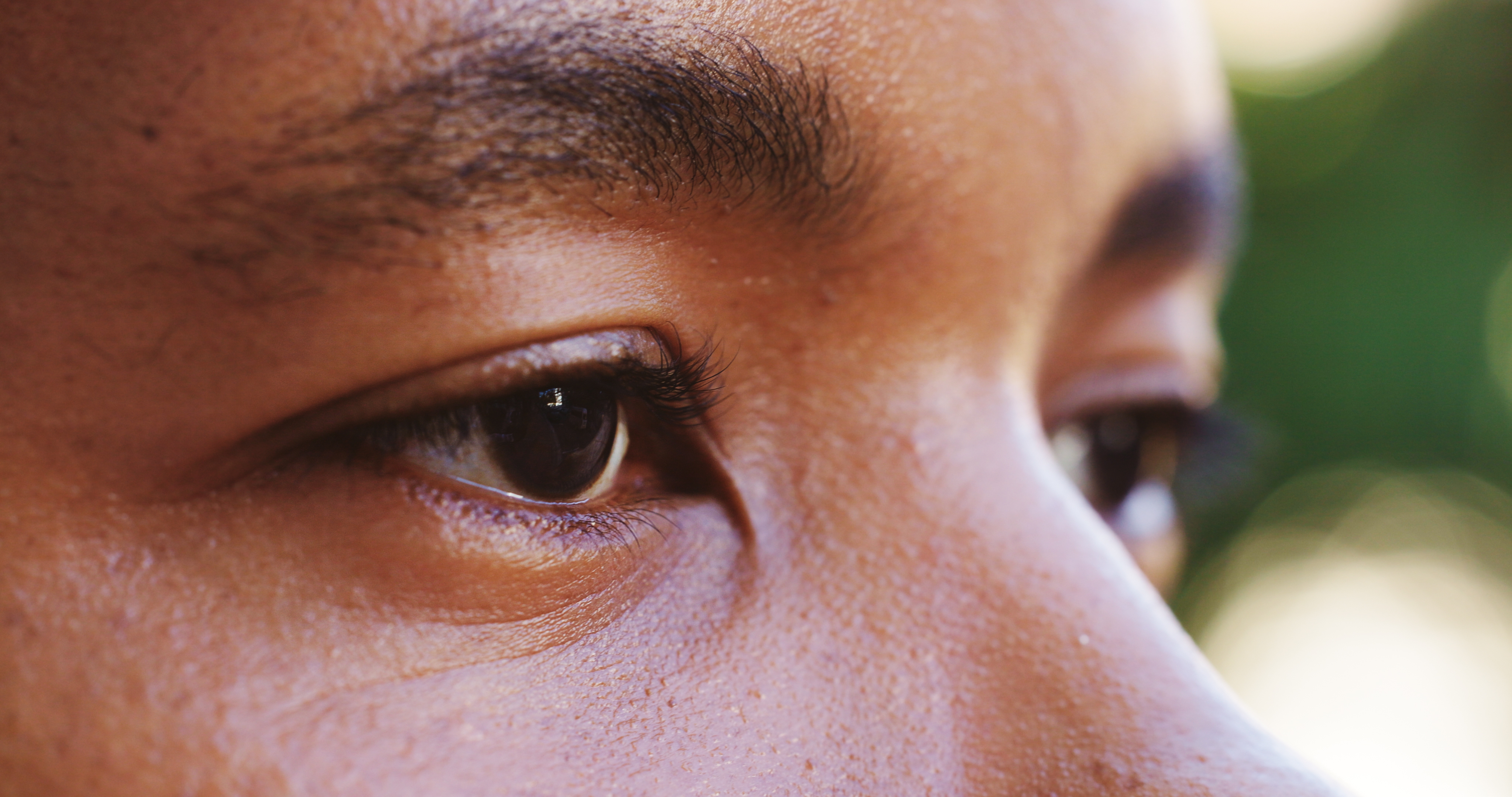 Close-up of a person's eyes, looking intently to the side. Skin texture is visible