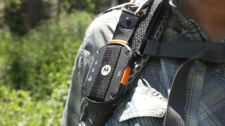 A Motorola Defy Satellite Link strapped onto a backpack, showing the orange SOS button.