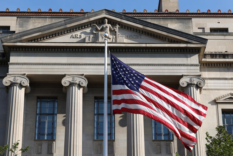 Kevin Lamarque/Reuters - PHOTO: A flag flies outside the Department of Justice building in Washington, Sept. 23, 2025.