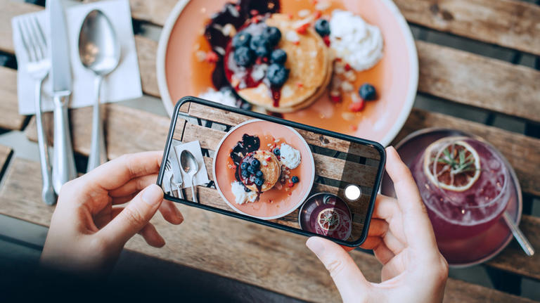 A person using an iPhone camera to take a photo of their breakfast.