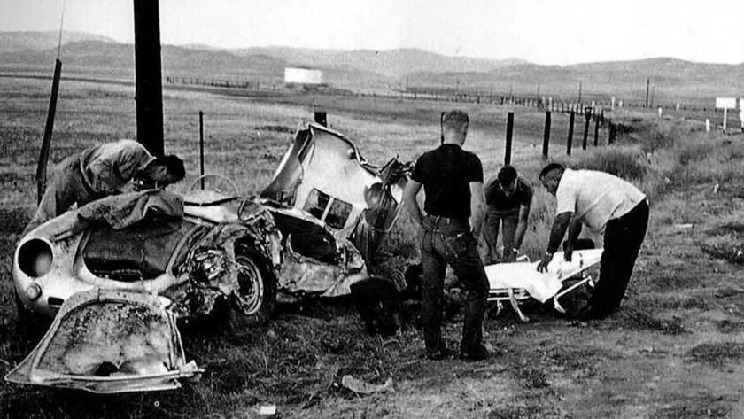 A black and white photo showing several men examining the remains of a car wreck