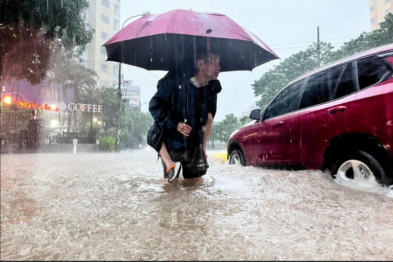 Ông Nguyễn Vân Nga (70 tuổi) đội mưa, cõng cháu khoảng 500 m, từ trường Tiểu học Đại Từ để về chung cư số 1 Nguyễn Cảnh Dị. Ảnh: Huy Mạnh