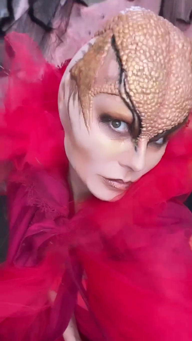 Heidi Klum in a red ruffled costume with an elaborate reptilian headpiece.