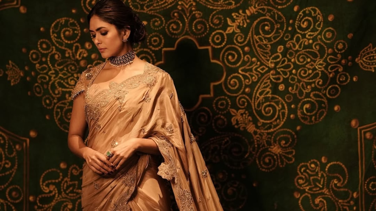 Mrunal wore this beige silk saree with delicate golden motifs and scalloped gold edges, paired with a half-sleeved blouse featuring tassels and subtle embroidery. The structured neckline added a contemporary touch to this timeless drape. (Image Source: Instagram/ mrunalthakur)