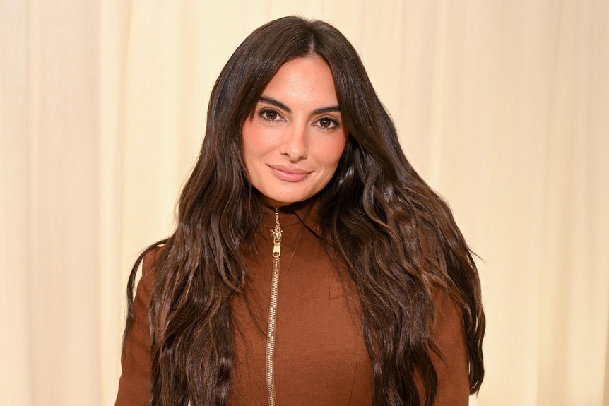 Paige DeSorbo smiling in a brown outfit.