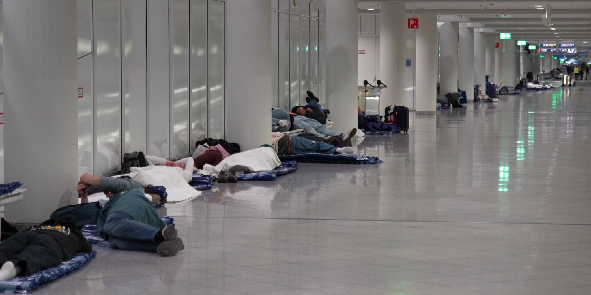 Menschen ruhen sich nach Drohnensichtungen am Flughafen München aus. Quelle: Enrique Kaczor/onw-images/dpa